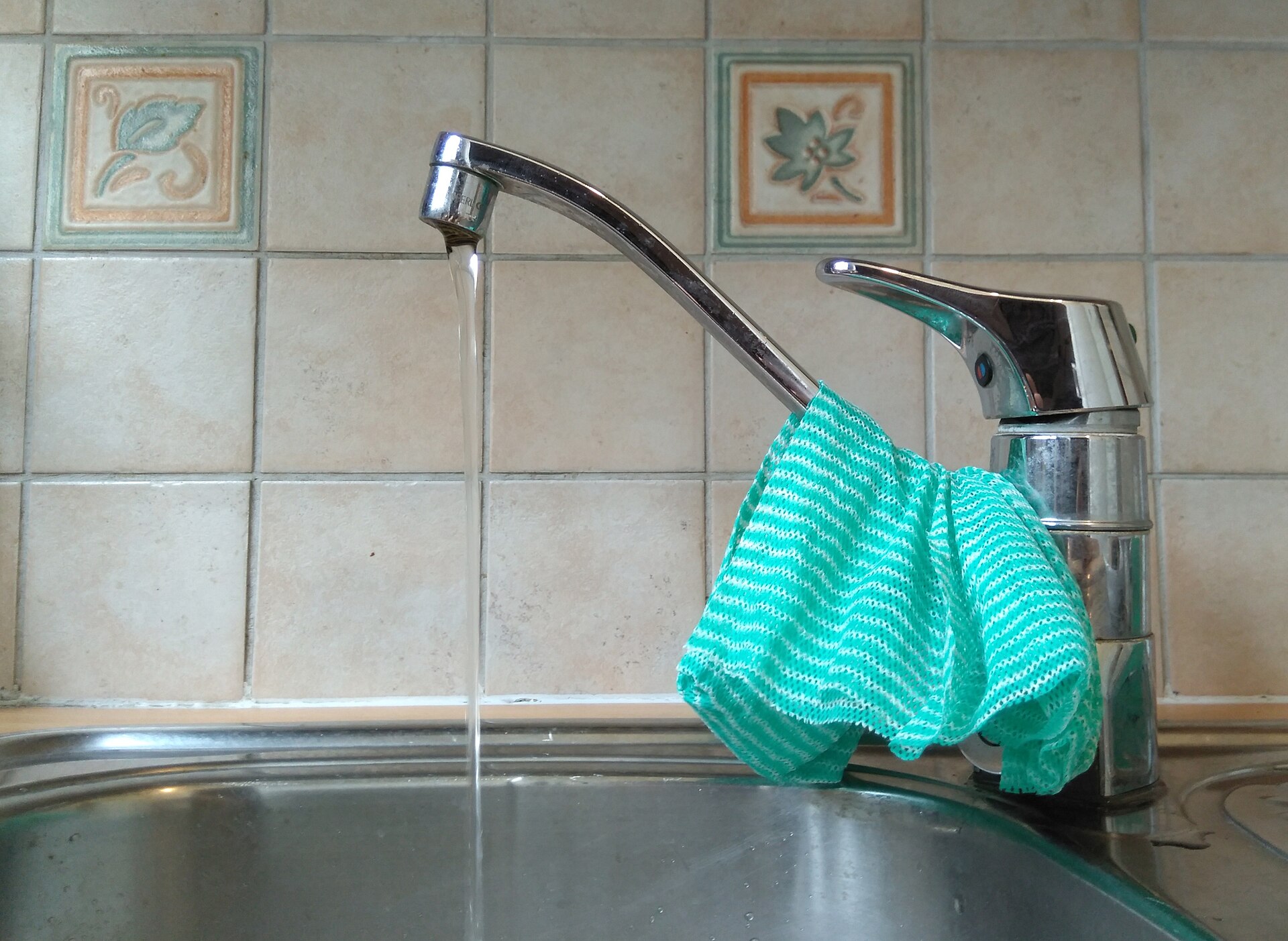 Water running from a kitchen tap into a steel sink